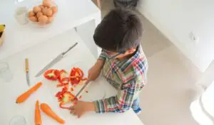 Child chops vegetables on a plastic cutting board