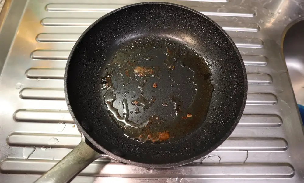 dirty non stick frying pan with grease splatter and food residue
