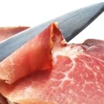 A chef's knife slicing ham