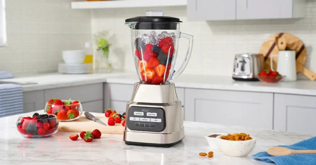 modern blender with strawberries and fruit ingredients on a kitchen table interior