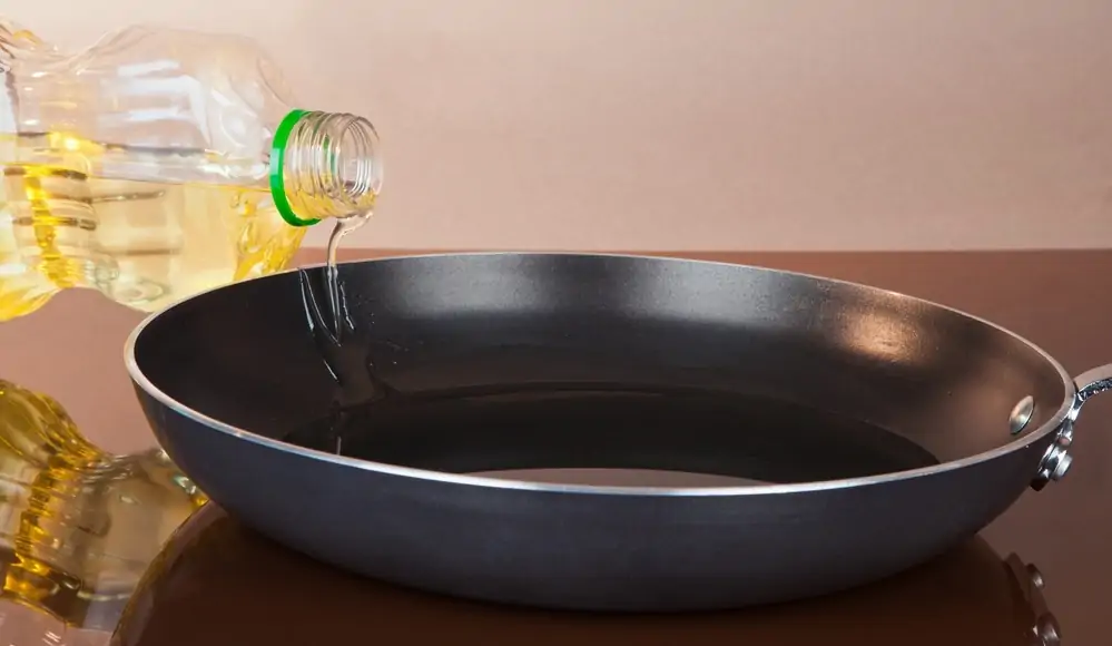 oIl being poured into a non stick pan for cooking